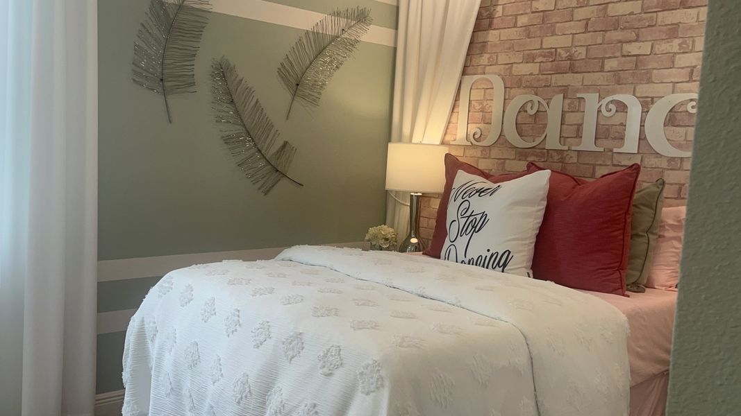 A cozy bedroom with decorative leaves, brick wallpaper, and plush bedding enhances its warm ambiance.