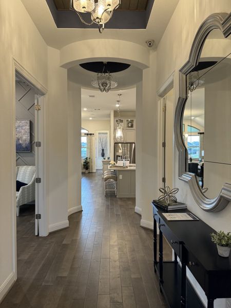 A hallway with elegant decor, featuring hardwood floors, decorative lighting, and a stylish mirror. A hallway with elegant decor, featuring hardwood floors, decorative lighting, and a stylish mirror.