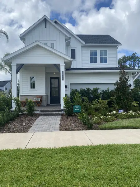 A charming white home with a landscaped front yard in Seven Pines 70' Rear Entry by David Weekley Homes (Jacksonville, FL).