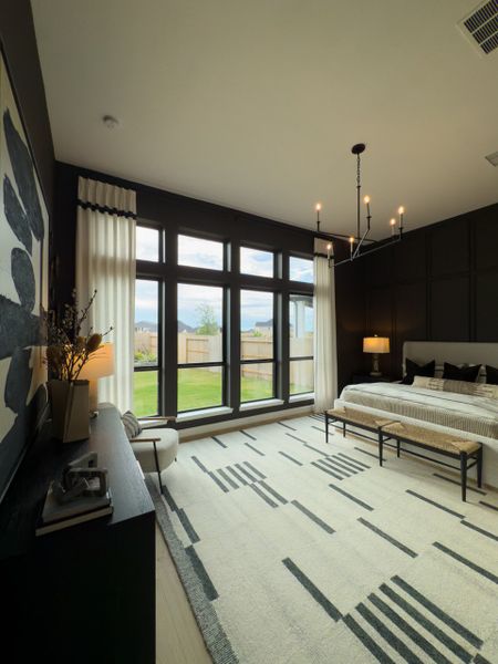 A spacious bedroom featuring large windows, modern lighting, and stylish decor with a cozy seating area. A spacious bedroom featuring large windows, modern lighting, and stylish decor with a cozy seating area.