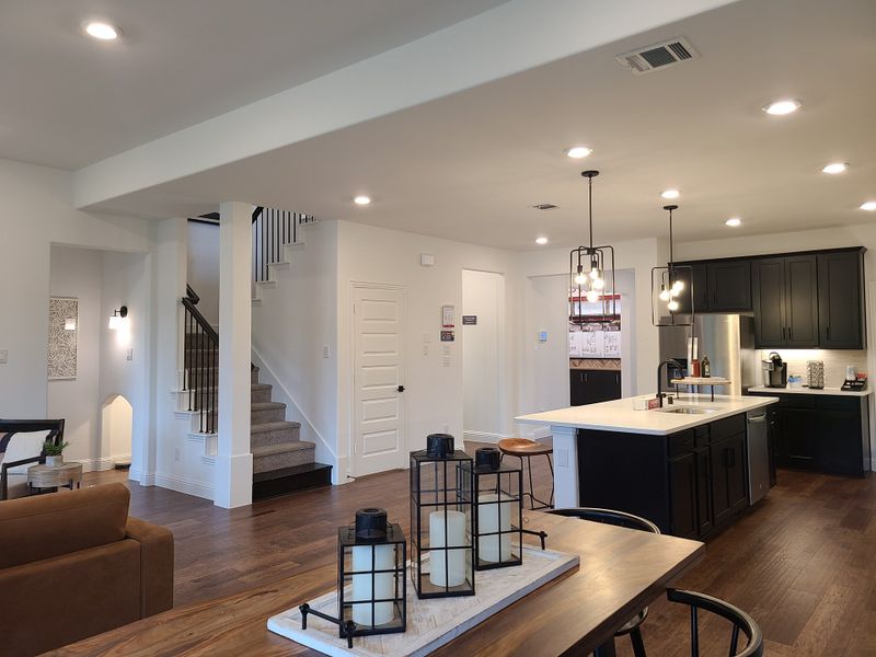 A modern open-concept living space with sleek black cabinetry, stylish pendant lights, and elegant wood flooring. A modern open-concept living space with sleek black cabinetry, stylish pendant lights, and elegant wood flooring.