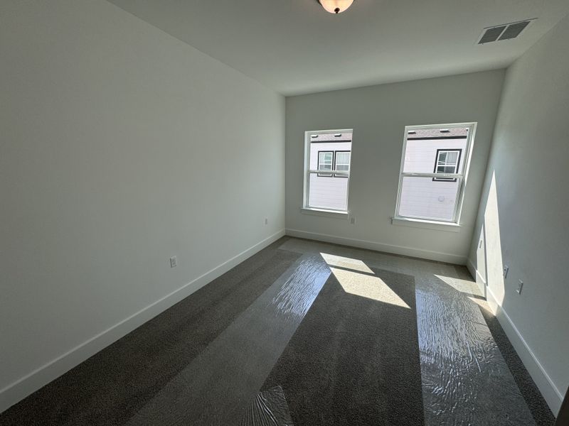 A bright, cozy room with plush carpeting, natural light from two large windows, and minimalist design. A bright, cozy room with plush carpeting, natural light from two large windows, and minimalist design.