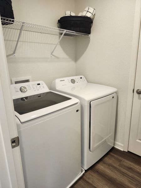 A compact laundry room with modern washer and dryer, highlighting a sleek open shelf for storage.