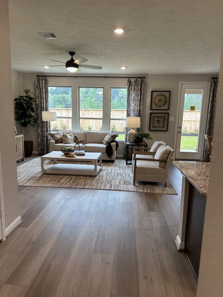 An inviting living room with light wood floors, cozy seating, and large windows offering scenic views. An inviting living room with light wood floors, cozy seating, and large windows offering scenic views.