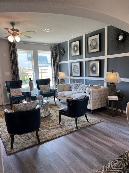 A stylish living room with tufted sofas, elegant armchairs, modern artwork, and warm lighting on wooden floors. A stylish living room with tufted sofas, elegant armchairs, modern artwork, and warm lighting on wooden floors.