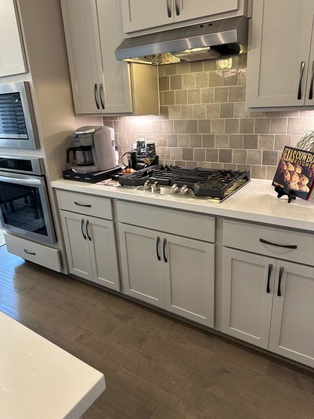 A modern kitchen featuring sleek cabinetry, a subway tile backsplash, and stainless steel appliances. A modern kitchen featuring sleek cabinetry, a subway tile backsplash, and stainless steel appliances.