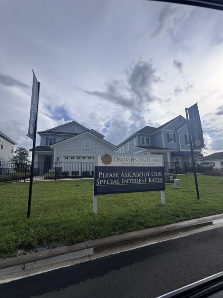 A modern grey home with sleek architecture and lush lawn in TrailMark by Dream Finders Homes (St. Augustine, FL).