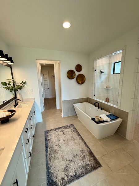 A modern bathroom featuring a freestanding tub, sleek double vanity, and elegant wall decor with warm lighting.