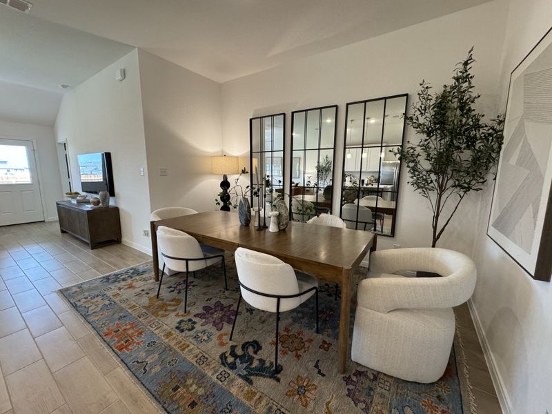 A chic dining area with a wooden table, elegant chairs, large mirrors, and a colorful patterned rug.