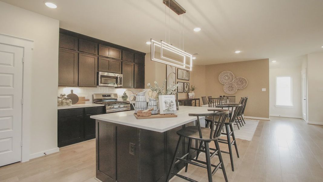 Experience sleek luxury with this kitchen's dark wood cabinetry and pendant lighting at Colony at Pinehurst.