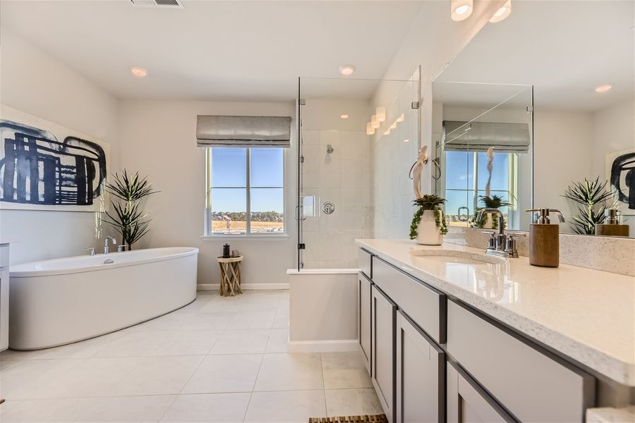 A bathroom with a tub sink and a large mirror.