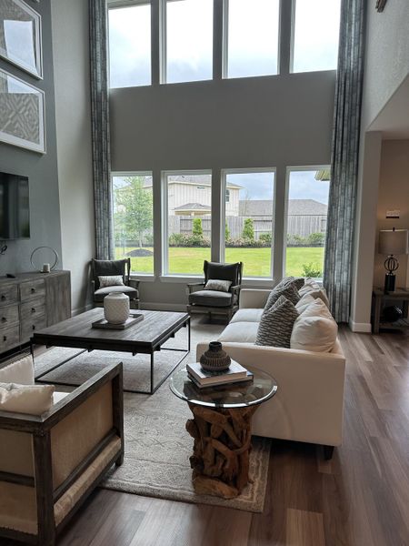 A spacious living room with lofty windows, modern furnishings, and elegant hardwood floors. A spacious living room with lofty windows, modern furnishings, and elegant hardwood floors.