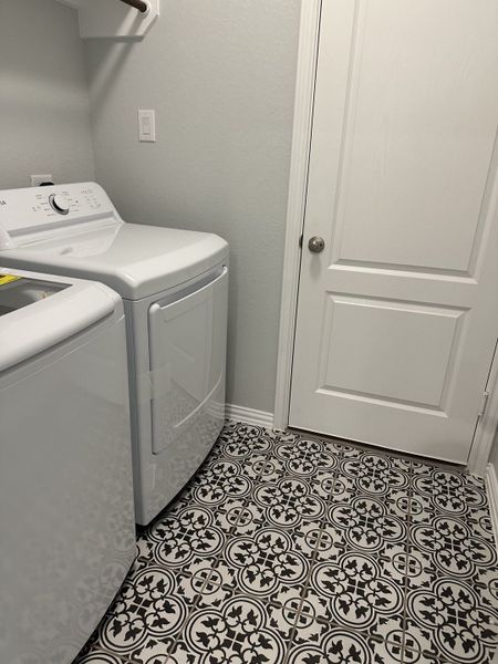 A sleek laundry room with patterned tiles, modern appliances, and soft gray walls. A sleek laundry room with patterned tiles, modern appliances, and soft gray walls.