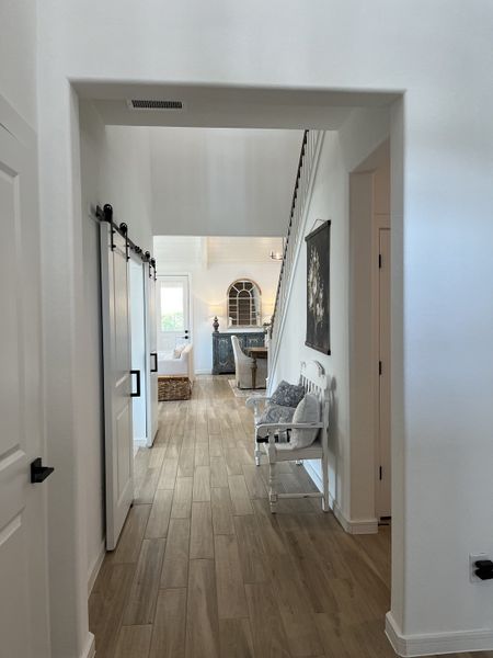 A bright hallway featuring wood floors, a cozy bench, and tasteful decor leading to an inviting living area. A bright hallway featuring wood floors, a cozy bench, and tasteful decor leading to an inviting living area.