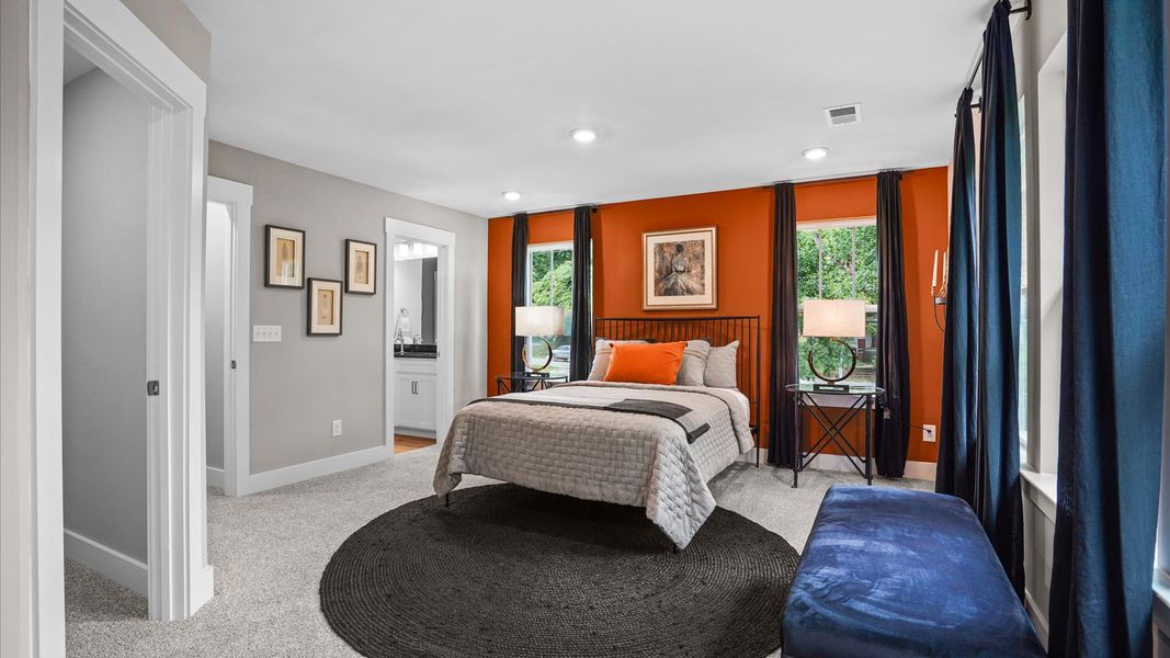 Cozy, inviting primary suite adorned with windows and plush carpet in two story townhome at Clayton Crossing by DRB Homes Cozy, inviting primary suite adorned with windows and plush carpet in two story townhome at Clayton Crossing by DRB Homes
