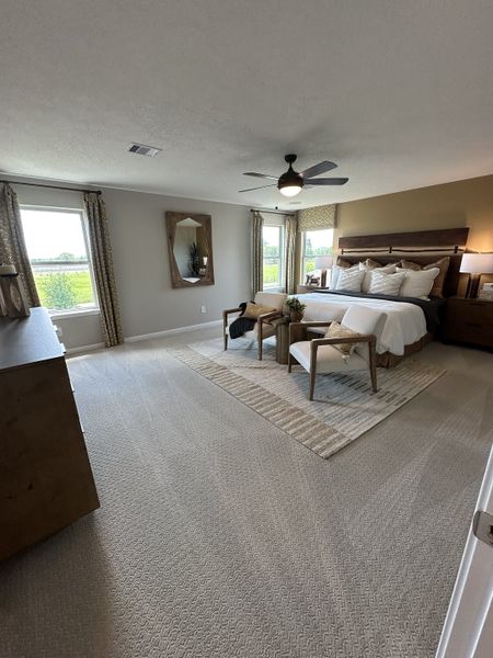 A spacious bedroom with a plush carpet, elegant furniture, and large windows for natural light.