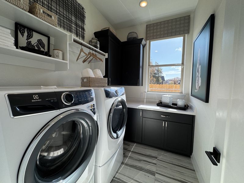 A modern laundry room with sleek appliances, built-in shelving, and elegant decor accents.