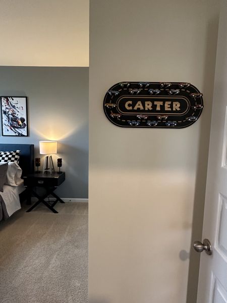 A cozy bedroom with a sports-themed sign, stylish wall art, and ambient lighting for a kid-friendly space.