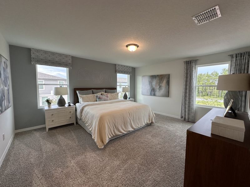 A spacious bedroom with soft carpeting, large windows, and elegant decor in calming neutral tones. A spacious bedroom with soft carpeting, large windows, and elegant decor in calming neutral tones.