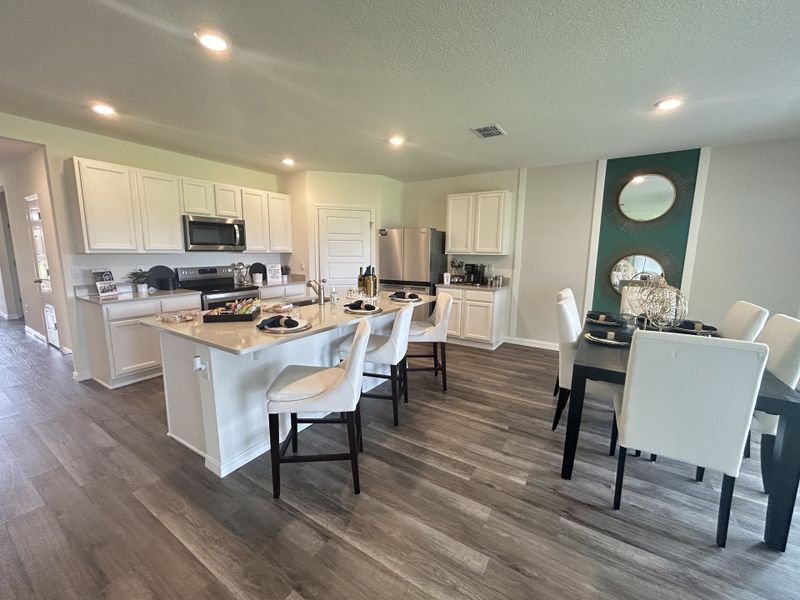 A modern kitchen and dining area with white cabinetry, a sleek island, and elegant seating.
