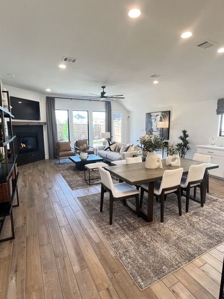 An inviting open-plan living area with wooden floors, cozy seating, a modern fireplace, and a dining space with elegant lighting. An inviting open-plan living area with wooden floors, cozy seating, a modern fireplace, and a dining space with elegant lighting.