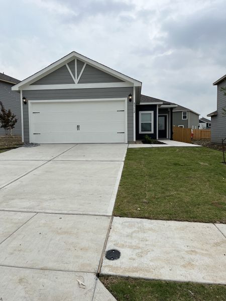 A charming gray home with a manicured lawn and a clean driveway in Big Sky Estates by LGI Homes (Ponder, TX).