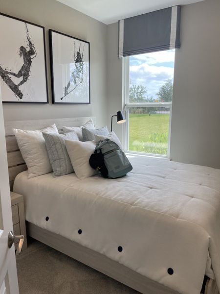 A cozy bedroom featuring modern art, plush bedding, and a large window with natural light. A cozy bedroom featuring modern art, plush bedding, and a large window with natural light.