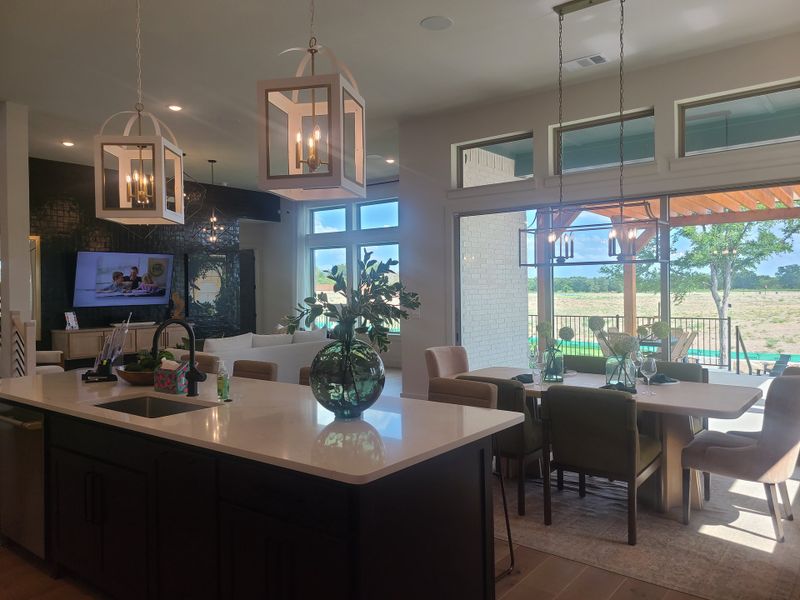 Modern open-plan kitchen and dining space with pendant lighting, large windows, and stylish decor. Modern open-plan kitchen and dining space with pendant lighting, large windows, and stylish decor.