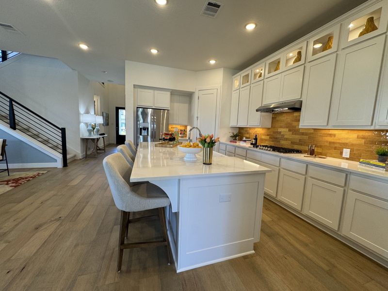 A modern kitchen with sleek white cabinetry, a large island, and warm wood floors, complemented by stylish lighting. A modern kitchen with sleek white cabinetry, a large island, and warm wood floors, complemented by stylish lighting.