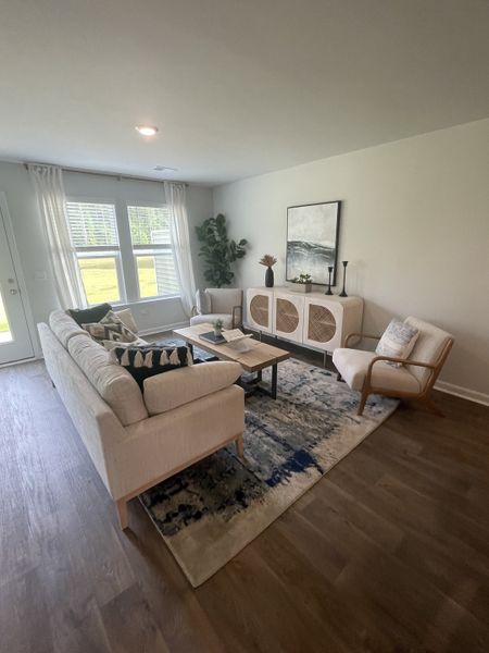 A cozy living room with a plush sectional, patterned rug, and modern decor. Bright natural light fills the space.