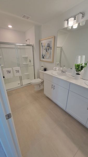 A modern bathroom with sleek white cabinetry, a spacious walk-in shower, and elegant decor elements.