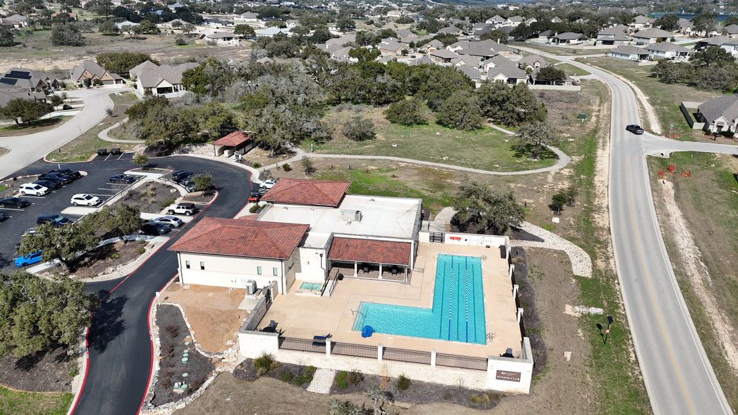An inviting community center with a pool and parking in The Grove at Vintage Oaks by Scott Felder Homes (New Braunfels, TX).