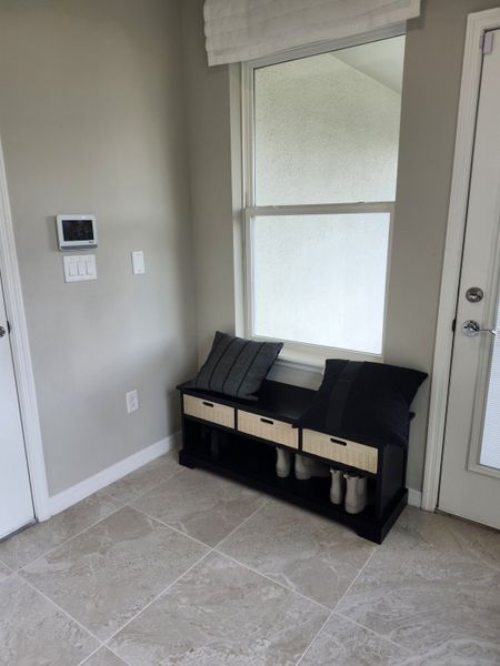 A cozy entryway with tile floors, a black bench, and soft pillows, offering a welcoming vibe. A cozy entryway with tile floors, a black bench, and soft pillows, offering a welcoming vibe.