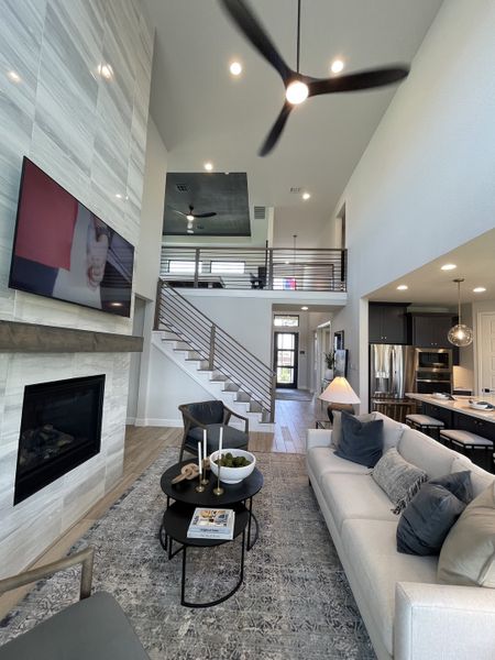 A modern living room with high ceilings, sleek fireplace, cozy seating, and stylish decor. A modern living room with high ceilings, sleek fireplace, cozy seating, and stylish decor.