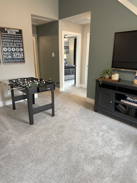 A cozy playroom with plush carpeting, a foosball table, and modern decor, perfect for relaxation and fun.