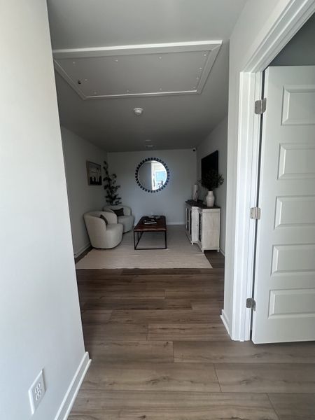 A cozy living room with sleek wood flooring, a circular mirror, and contemporary furnishings. A cozy living room with sleek wood flooring, a circular mirror, and contemporary furnishings.