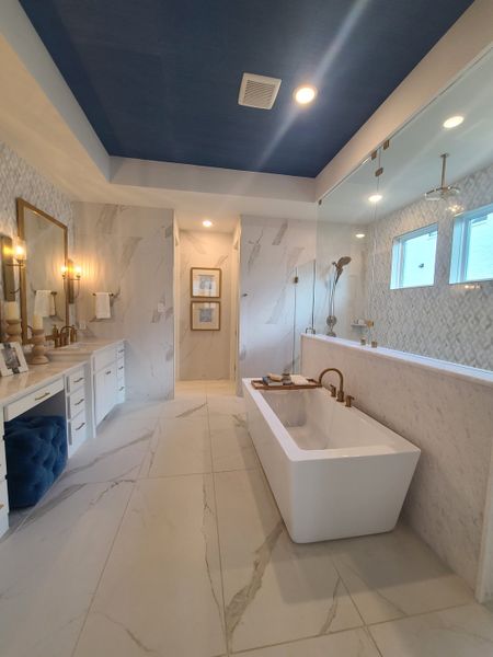 A luxurious bathroom featuring a freestanding tub, elegant vanity, bold blue ceiling, and sleek marble accents.