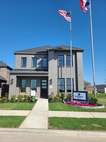 A modern gray brick home with manicured landscaping in Cross Creek Meadows 55' & 60' Series by Normandy Homes (Celina, TX).