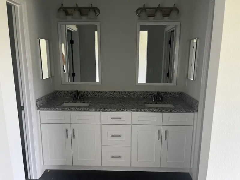 Chic bathroom with a granite double vanity, white cabinetry, and modern light fixtures. Chic bathroom with a granite double vanity, white cabinetry, and modern light fixtures.