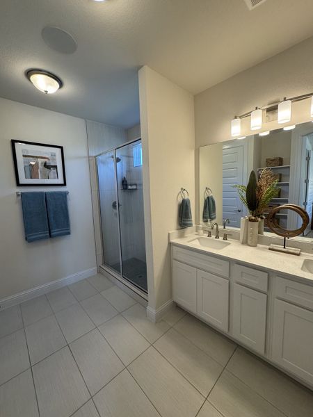 A spacious bathroom with a modern glass shower, double sink vanity, and elegant lighting.