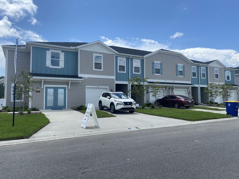 Two-story modern townhomes with blue accents and garages in Mill Creek North Townhomes by Lennar (Jacksonville, FL).