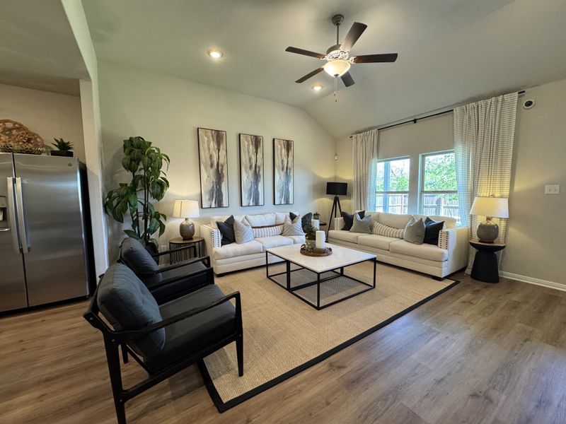 A cozy living room with neutral sofas, modern art, and stylish lighting on warm wood flooring.