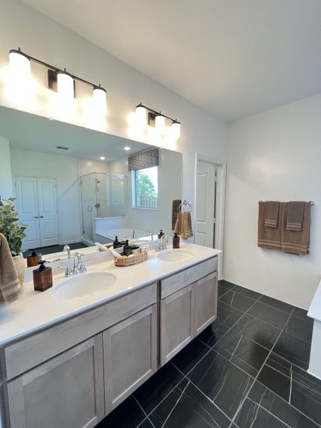 A modern bathroom featuring a dual-sink vanity, sleek black tile flooring, and elegant lighting.