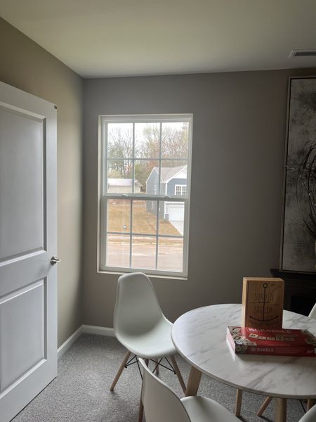 A cozy room with a window view, featuring a white round table, modern chairs, and games, creating a serene atmosphere. A cozy room with a window view, featuring a white round table, modern chairs, and games, creating a serene atmosphere.
