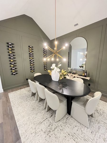 A chic dining room with a sleek black table, unique chairs, modern chandelier, and elegant wall-mounted wine racks.