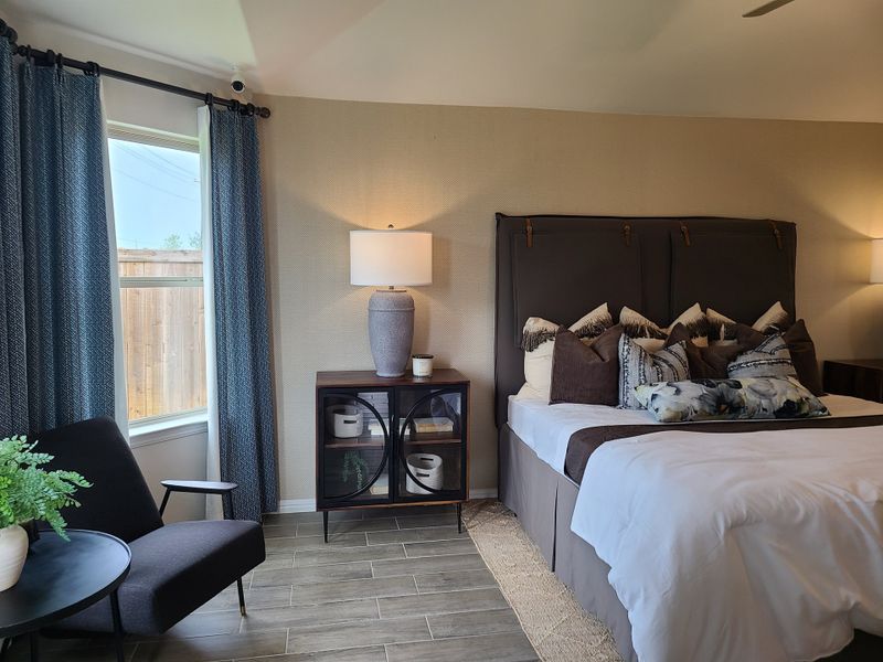 Cozy bedroom with a plush bed, elegant blue curtains, modern chair, and stylish accents creating a serene retreat. Cozy bedroom with a plush bed, elegant blue curtains, modern chair, and stylish accents creating a serene retreat.