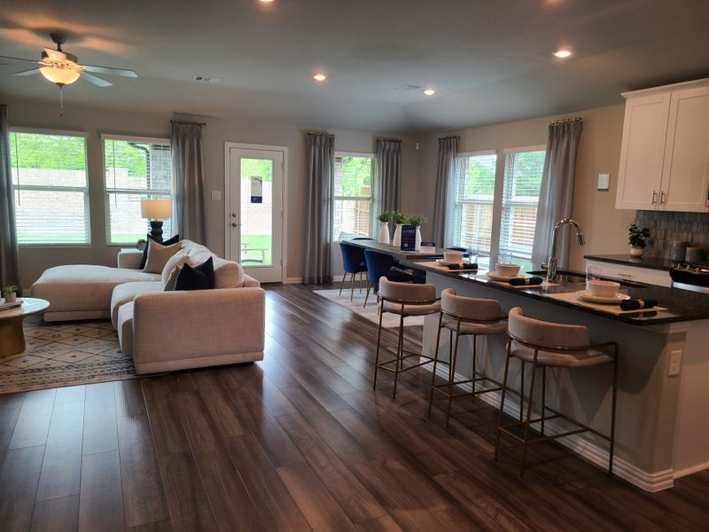 A modern open-plan living space with a cozy sectional sofa, sleek kitchen island, and abundant natural light.
