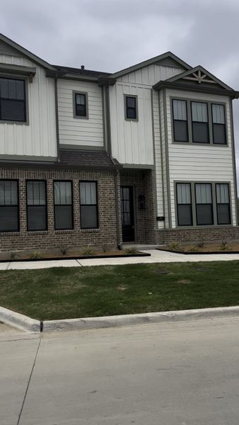 A modern home with brick and siding in Collin Creek by Ashton Woods (Plano, TX).
