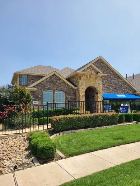 A beautiful brick home with stone accents and lush landscaping in Williamsburg by D.R. Horton (Fate, TX).