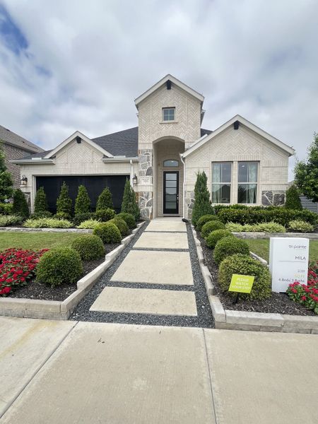 A beautiful light brick home with manicured landscaping in the Garden Collection at Union Park by Tri Pointe Homes (Little Elm, TX).